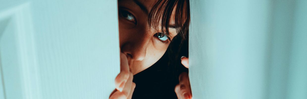 vrouw-spiekt-achter-blauwe-gordijnen