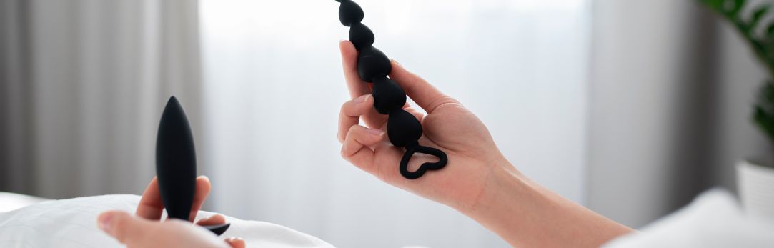 vrouw-houdt-twee-zwarte-buttplugs-vast-in-bed